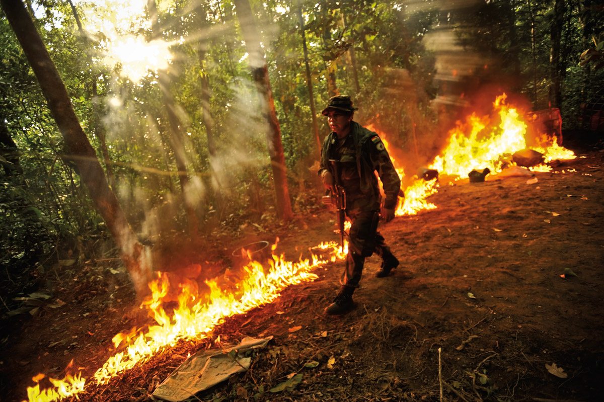 Bolivian FELCN Special Forces agent, Juan Pablo Claros LÛpez, 25, lights a line of gasoline on fire during a raid to burn and destroy a cocaine-base processing lab in the outskirts of Villa Nuevo Horizonte, a dangerous area in the department of Santa Cruz were narcotraffiking runs rampant. FELCN officials report it is the area of Bolivia most thickly dense of narcotraffickers and cocaine-base processing laboratories.  FELCN police commonly referred to it as a "narco pueblo".