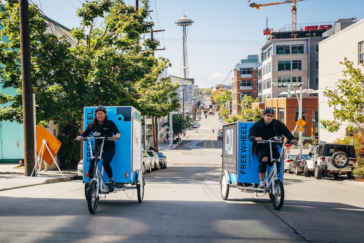 man and woman ride cargo bikes in Seattle